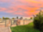 The GreenAcres facility and paddock fencing silhouetted against a pink Colorado sunset